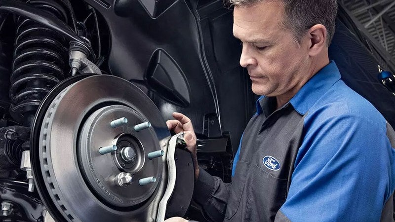 Ford technician fitting a genuine Ford brake rotor and pad, OEM Ford parts for drivers near Los Lunas, NM